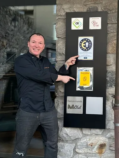 Eugen Ligonnet devant le panneau des distinctions de l’Hôtellerie de Châtonneyre, où figurent la plaque Euro-Toques et le Gault&Millau 2026.